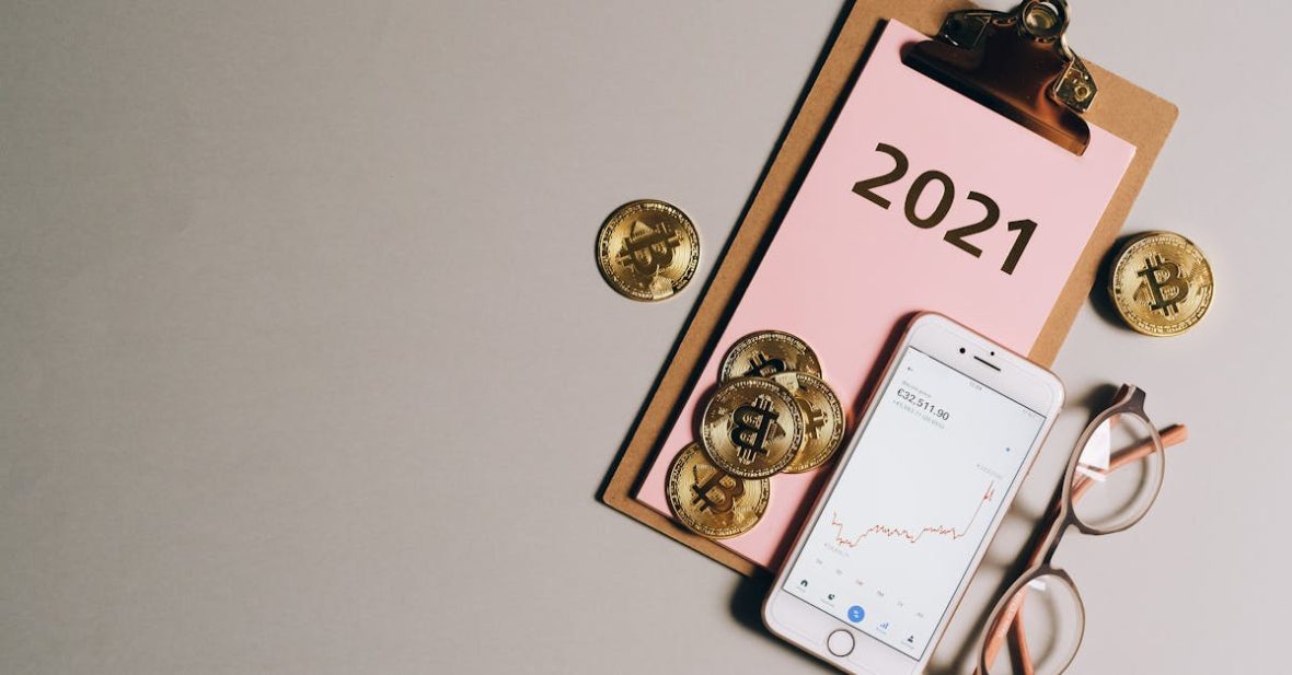 flat-lay-of-bitcoins-smartphone-eyeglasses-and-clipboard-with-2021-text-symbolizing-cryptocurren-2